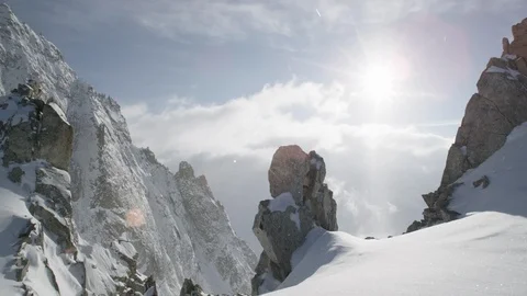Snow falling on the rocky mountain top on a sunny day Stock Footage 113218945