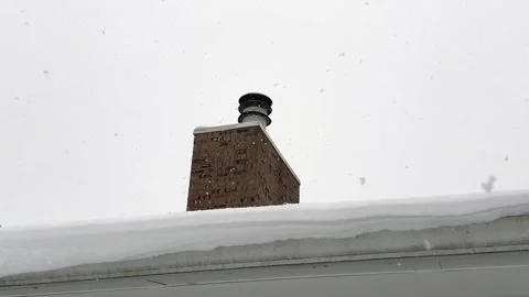 Snow falling on a rooftop by a chimney Stock Footage 328365023
