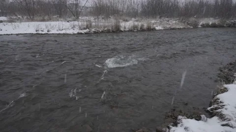 Snow falling into a seething river Stock Footage 142258942