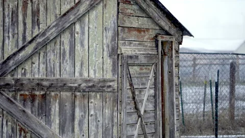 Snow falling in slow motion in front of old rustic wood barn shed Video stock 176420268