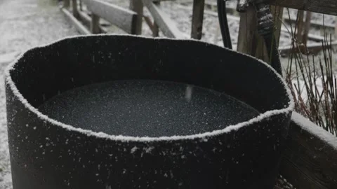 Snow Falling Slowly into a Frozen Barrel with Ice in a Garden Stock Footage 242503569