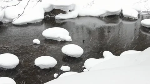 Snow falling on snow-covered rocks river rocks in Japanese winter landscape Stock Footage 303256532