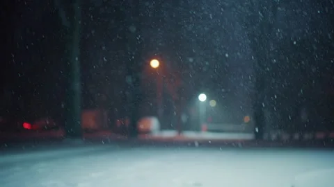Snow falling steadily in an empty park at night. Streetlights glow softly in the Stock Footage 329391542