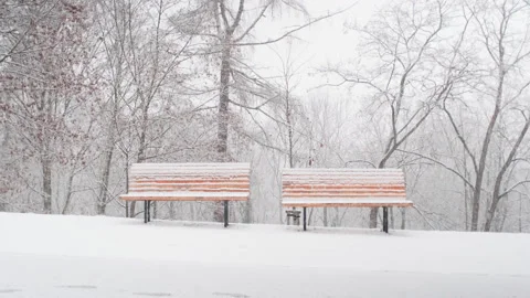 Snow falling on two yellow benches in a surreal park Stock Footage 147926430