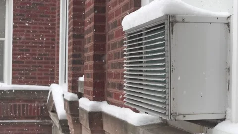 Snow falling on a window air conditioner unit on a brick building. Stock Footage 327635474