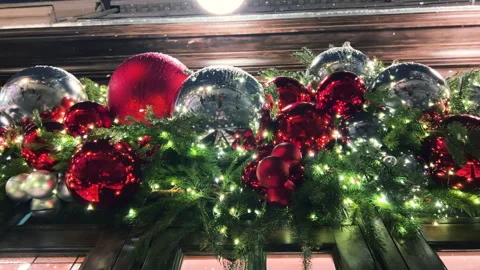Snow falls against the backdrop of a building decorated with garlands, lights. Stock Footage 295834357