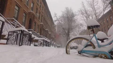 Snow falls on a bicycle parked on a brownstone block in Brooklyn Vidéo 147614558