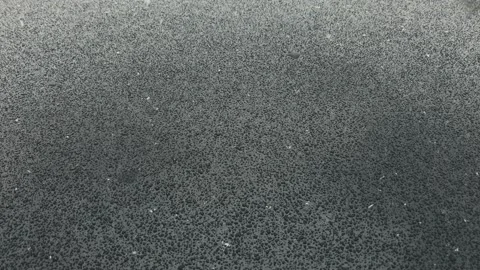 Snow falls on a black surface and melts metal black drops Stock Footage 175966772