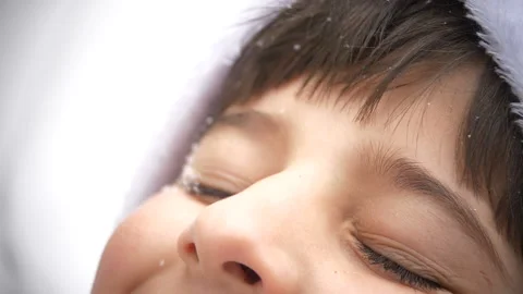 The snow falls on the boy's face Stock Footage 88435667