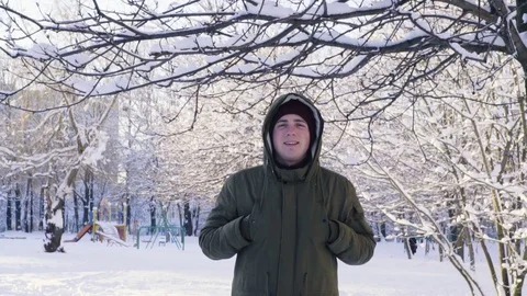 Snow falls from the branch. A man covers his head with a hood. Slow motion. Stock Footage 84976233