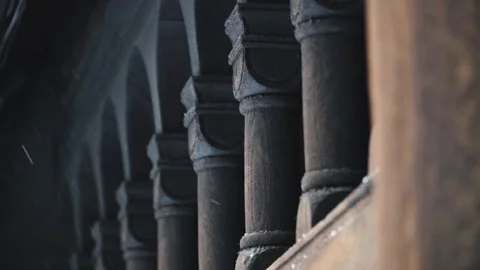 Snow falls in front of wooden columns of an ancient building Stock Footage 243572789