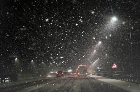 Snow falls on the highway on December night Stock Photos