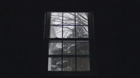 Snow Falls Outside a Silhouetted Window Stock Footage 76466187