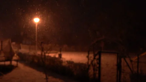 Snow falls from the sky at night falls into the light of a street lamp, large Stock Footage 146972239