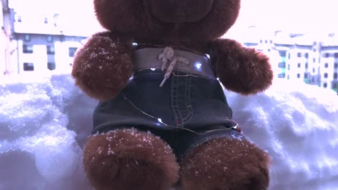 Snow falls on a teddy bear sitting on the balcony. Stock Footage 327814118