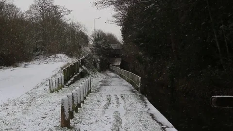 Snow falls on tow path next to can, bridge in the background Stock Footage 83408940