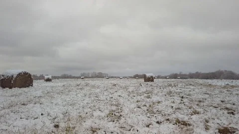 Snow field with stacks of straw on the background of a gloomy winter sky Vídeos de archivo 123039081