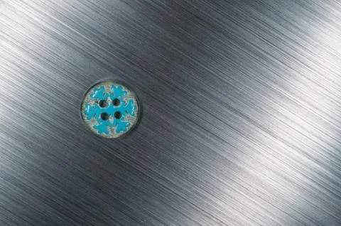 Snow flake sewing button on brushed metal background texture Stock Photos