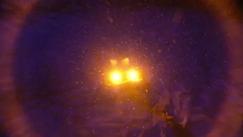 Snow flakes fly in the light of a yellow street lamp in a city park at night. Stock Footage 152123132