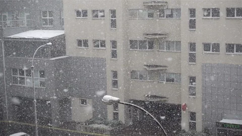 Snow flakes fly in slow motion on a city building Video stock 140756555