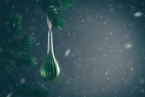 Snow is gently falling on a dark, elegant green christmas ornament hanging fr Stock Photos