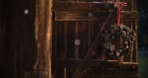 Snow gently falling on rustic barn with christmas wreath Stock Footage