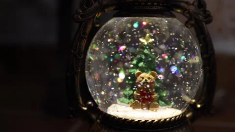 Snow globe with a bear and a tree at a cozy setting during the holiday season 库存影片 324957077