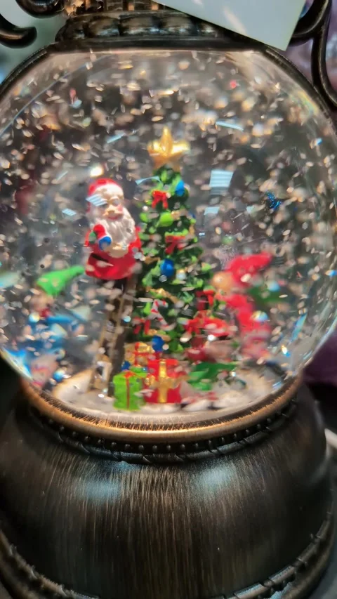 Snow globe with Christmas tree, Santa, and gifts on display during holiday Stock Footage 331235990
