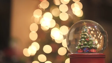 Snow globe shook in front of a bokeh of Christmas tree lights Stock Footage 120952975