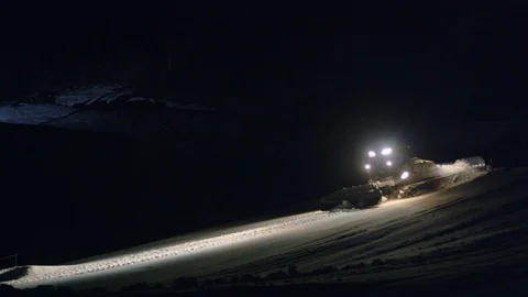 Snow groomer machine rides down mountain at night Stock Footage 116786237
