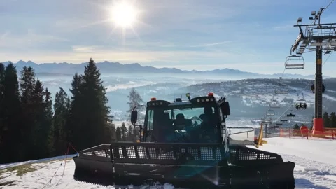 Snow grooming machine preparing ski slope near Zakopane with chairlift and .. Stock Footage 324445966