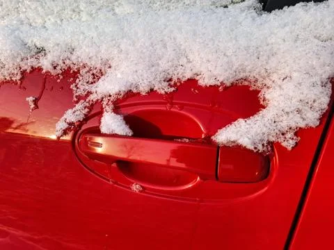 Snow has settled on the side window and door handle of the red car Photos