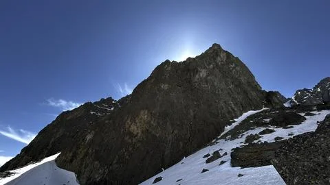Snow hiding from the spring sun behind a rock Stock Photos