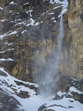 Snow , ice and stones  falling  from a vertical mountain wall Stock Photos