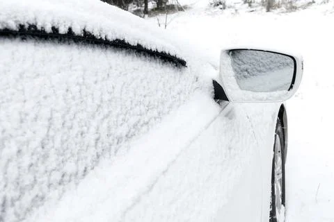 Snow layer on rearview mirror, windshield, window of sedan, car in backyard d Stock Photos