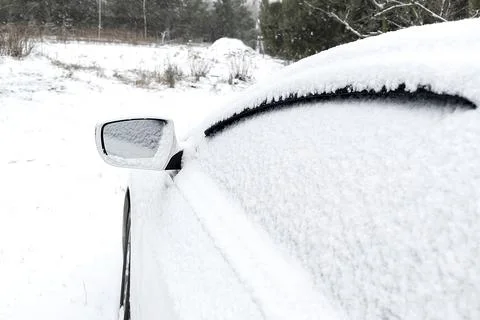 Snow layer on rearview mirror, windshield, window of sedan, car in backyard d Stock Photos