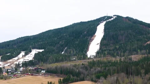 Snow lined ski slope cuts forested mountainside early spring fields contrast Stock Footage 327624718