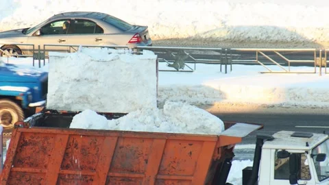 Snow loader transferring pile of white snow into dump truck for removal of Stock Footage 328359412