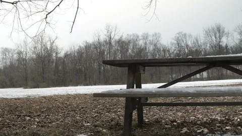 Snow melting off of desolate picnic bench framed right Video stock 104317979