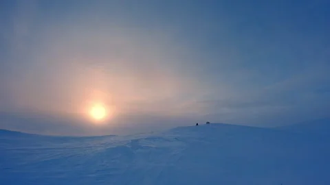 Snow mobile drive fast to the mountain top in Norway, large low Sun in fros.. Stock Footage 253931109