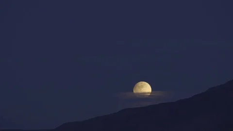 Snow Moon rises above the mountain, thru the clouds in partial Eclipse, 4k, TL Stock Footage