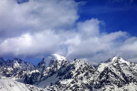 Snow mountaims in clouds at sun winter day Stock Photos