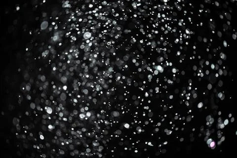 Snow or rain bokeh texture overlay on black background. Stock Photos