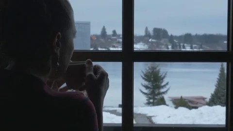 The snow outside the window and hot tea. Young woman with Cup of hot drink Stock Footage 70688685