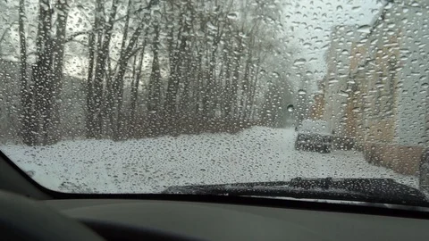 Snow outside the window turns into drops of water on the glass of the car. We ob Stock Footage 100010492