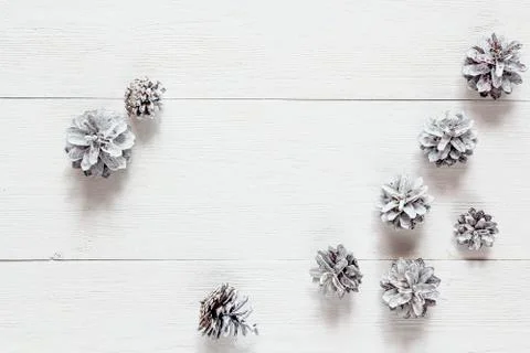 Snow painted pine cones on rustic white wood table. Space for text. Top view. Stock Photos