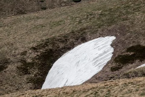 Snow patch resting on a grassy hillside in a mountainous region during spri.. Stock Photos