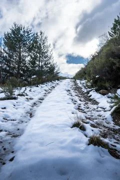 Snow path winding through winter mountain landscape Stock Photos
