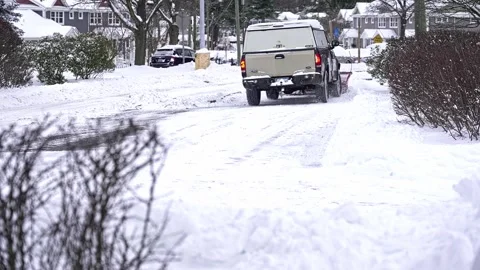 A snow plow clears a path while snow piles up on nearby bushes Stock Footage 325682631