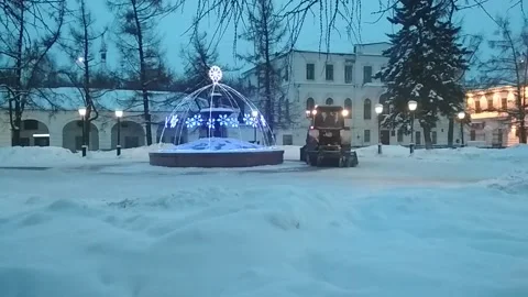 Snow plow tractor cleans road from snow around the fontane in the winter Stock Footage 148412021